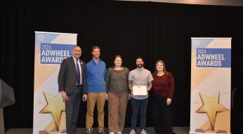 Photo of GoTriangle employees holding AdWheel Award on stage.